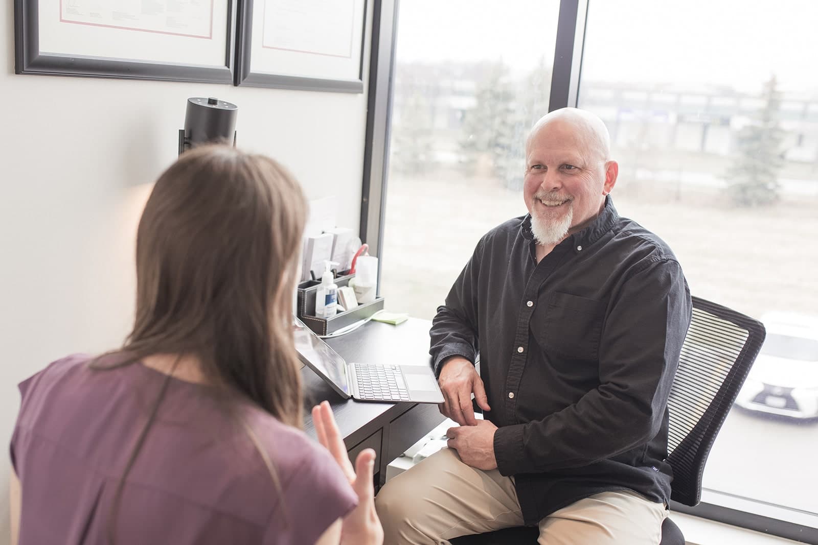 Practitioner in conversation with a smiling patient in a bright office
